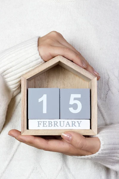 15 de febrero en el calendario. la chica sostiene un calendario de madera. Día Internacional del Cáncer Infantil, Día Nacional de la Bandera de Canadá — Foto de Stock