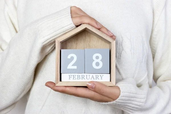 28. Februar im Kalender. Das Mädchen hält einen Holzkalender in der Hand. Tag der seltenen Krankheiten, Faschingsdienstag, internationaler Pfannkuchentag — Stockfoto