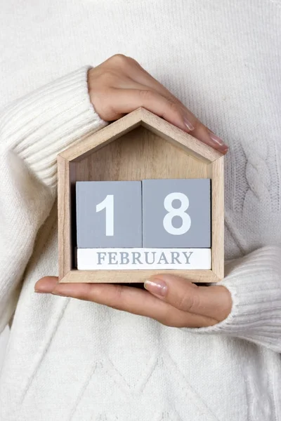 18 Φεβρουαρίου στο ημερολόγιο. το κορίτσι κρατά ένα ξύλινο ημερολόγιο. Παγκόσμια ημέρα για την προστασία των θαλάσσιων θηλαστικών — Φωτογραφία Αρχείου