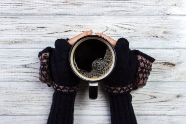 Kadın elinde bir fincan kahve ahşap arka plan üzerinde tutarak eldivenler