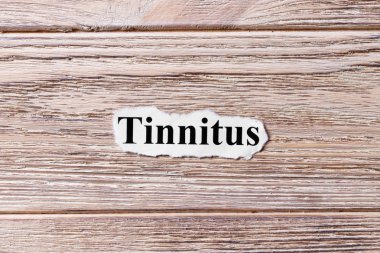 Kulak çınlaması kelime kağıt üzerinde. kavram. Tinnitus kelimelik bir ahşap arka plan