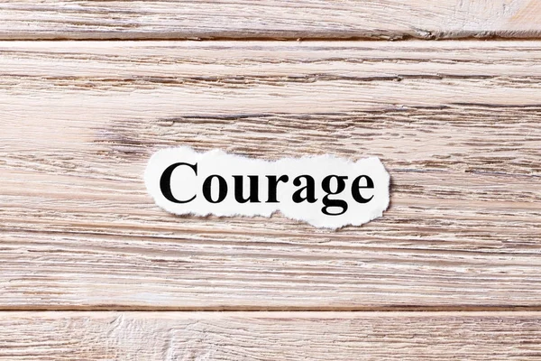 COURAGE of the word on paper. concept. Words of COURAGE on a wooden background