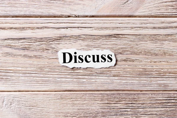 DISCUSIÓN de la palabra en papel. concepto. Palabras de DISCUSS sobre un fondo de madera — Foto de Stock