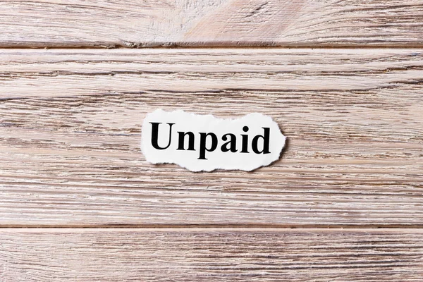 Kağıt üzerinde kelimenin ödenmemiş. kavram. Unpaid kelimelerin ahşap arka plan üzerinde
