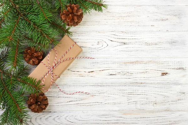 Çam kozalakları ve çam dalları ile karanlık rustik ahşap masa üzerinde Noel hediyeleri sarılmış. Metniniz için kopya alanı ile — Stok fotoğraf