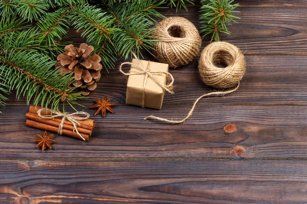 Χριστούγεννα παρόν πλαίσιο και έλατα κλαδιά με κανέλα και γλυκάνισο σε ρουστίκ ξύλινα φόντο. επίπεδη lay. Εποχιακοί Χαιρετισμοί έννοια. χειμερινές διακοπές — Φωτογραφία Αρχείου
