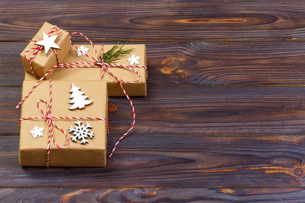 Tre scatole festive in carta di granchio decorate con fiocchi di neve e stella sul tavolo di legno. Vista dall'alto — Foto Stock