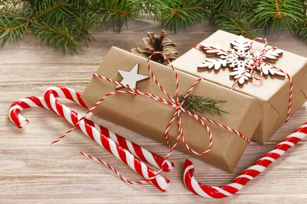 コピー スペースを持つ木製の背景にクリスマス ギフト用の箱とお菓子のモミの木の枝の杖します。 — ストック写真