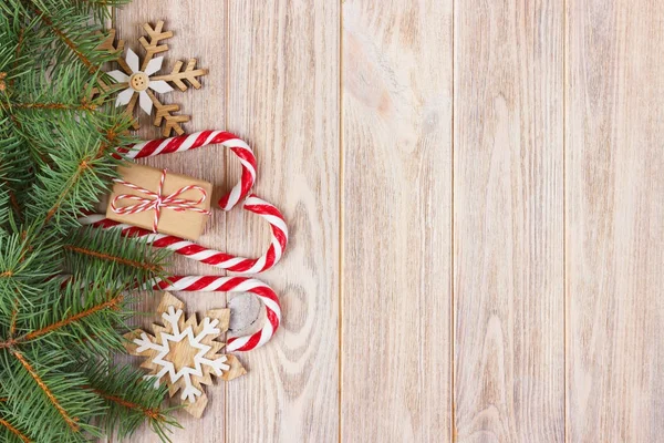 Caixa de presente de Natal, cana-de-açúcar com floco de neve e ramo de abeto na mesa de madeira — Fotografia de Stock
