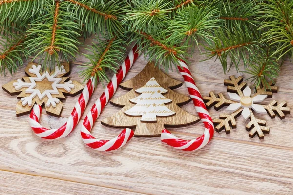 Bastoncini di zucchero natalizio e fiocchi di neve su uno sfondo di legno — Foto Stock