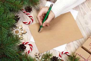 Noel Baba'ya bir mektup yazma eller. Ahşap arka plan üzerinde Noel hediyeleri. Yukarıdan görüntülemek