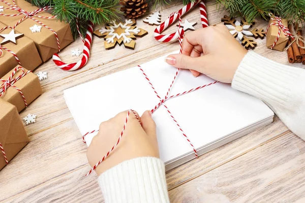 Birçok zarf ip ile bağladılar. Yakın çekim yukarıdan famale el ile zarf. Çam koniler ve Noel dekorasyonu eski ahşap tablo, Resepsiyon