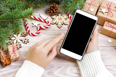 Kadın alıcı kopya alanı ile akıllı telefon ekranında sipariş yapar. Noel online alışveriş. Kadın için Noel hediyeleri satın alır. Kış tatil satış
