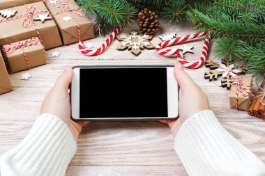 Cep telefonu tutan eller. Kadın Noel dekorasyonu ayaklarda. Üstten Görünüm. Rahat Noel evde