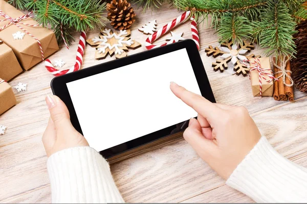 Tablet computer in girl hands. tablet computer with red gift box, christmas candy and fir branches. Free space for text. top view. Copy space. Closeup