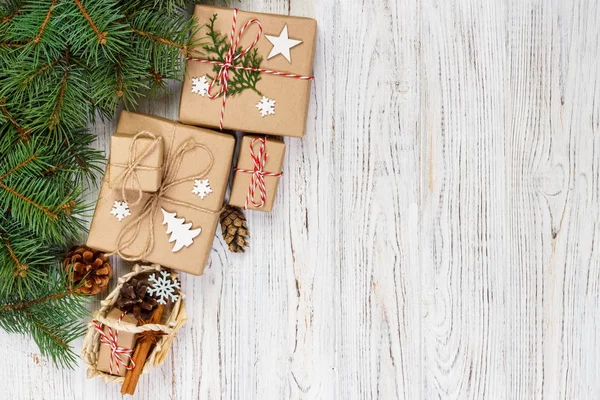 Vánoční dárkové krabice a jedle větev stromu s košíkem na dřevěný stůl — Stock fotografie