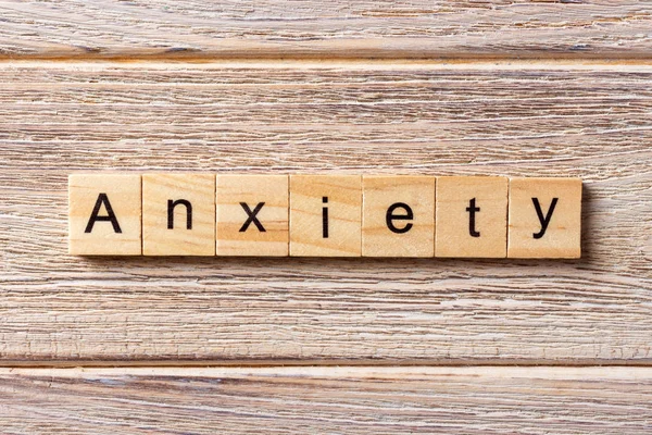 Слово ANXIETY, написане на дерев'яному блоці. Текст ANXIETY на столі, концепція — стокове фото