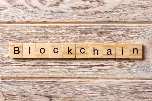 Tahta blokta bloklama kelimesi yazılı. Tablo üzerinde BLOCKCHAIN metni, konsept