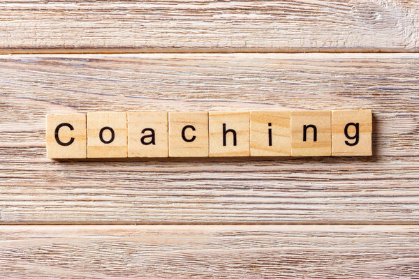 Учебное слово, написанное на деревянном блоке. КОАЧИНГ текст на столе, концепция