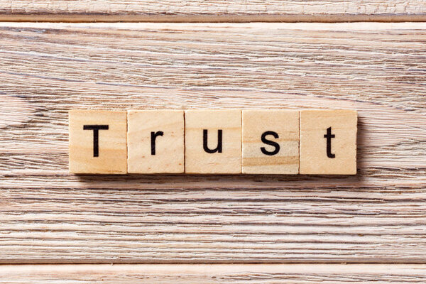 TRUST word written on wood block. TRUST text on table, concept