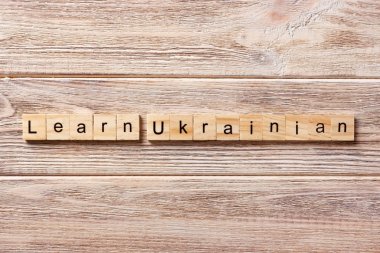 learn UKRAINIAN word written on wood block. learn UKRAINIAN text on table, concept clipart