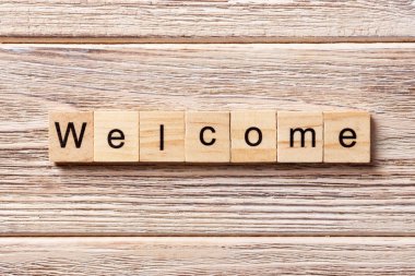 Ahşap blok üzerinde yazılı kelime hoş geldiniz. Hoş geldiniz metni masaya, kavram