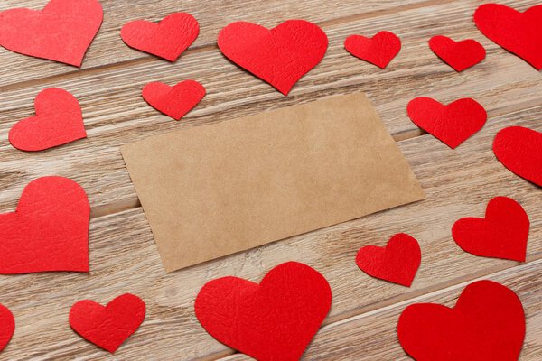 Valentines day background. Red hearts and empty letter on wooden background. Flat lay composition with copy space