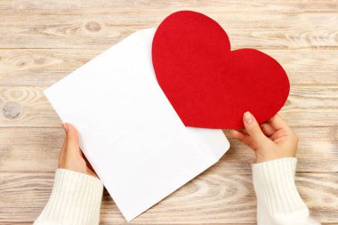 Bir kadın eli tutun açık bir zarf ve kartpostal ahşap masa, üstten görünüm