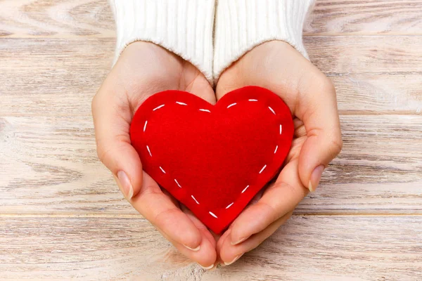 Corazón rojo en las manos primer plano sobre fondo de madera — Foto de Stock