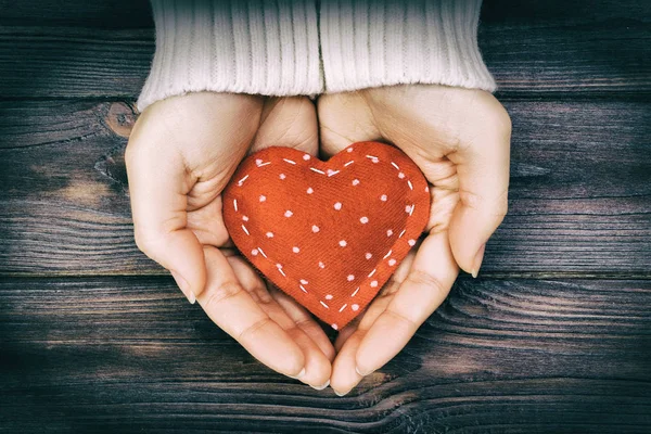 Chica mano sosteniendo rojo corazón forma vintage tono — Foto de Stock