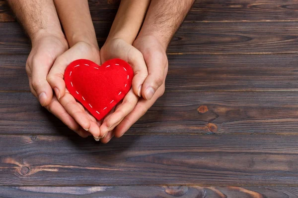Amor, concepto familiar. Primer plano de las manos de hombre y mujer que sostienen el corazón de goma roja juntos —  Fotos de Stock