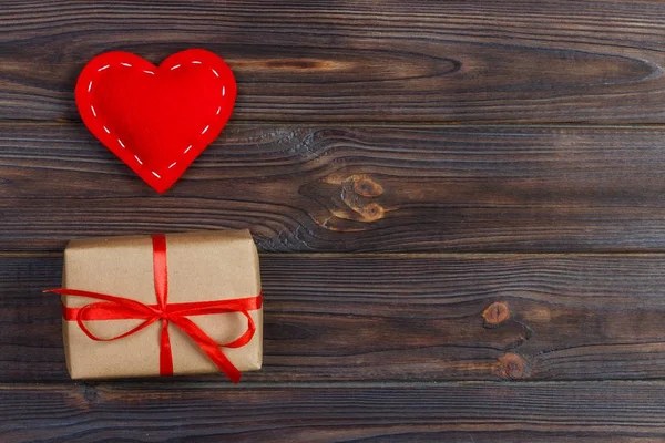 Confezione regalo con cuori in tessuto su tavolo in legno nero — Foto Stock