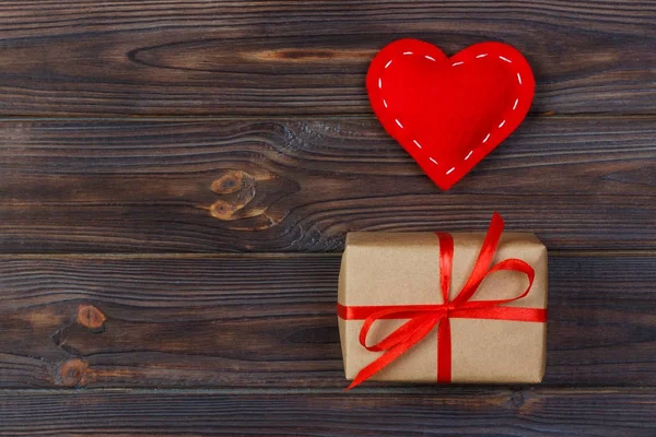 Heart and gift box with red ribbon on wooden background — Stock Photo, Image