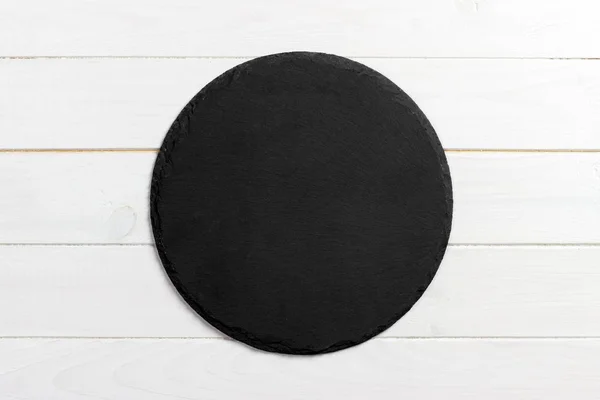Zwarte leisteen ronde steen op houten achtergrond, bovenaanzicht, kopie ruimte — Stockfoto