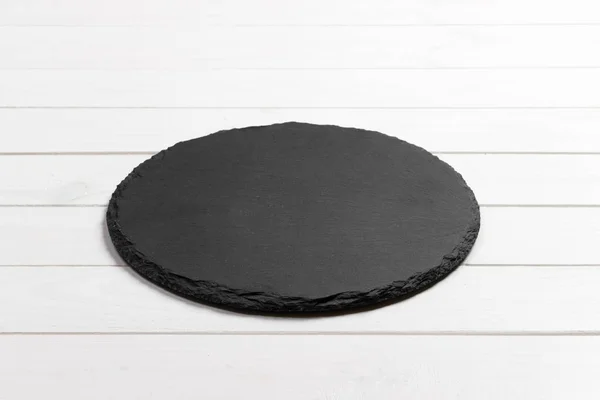 Slate plate on table. black slate stone on wooden background. copy space