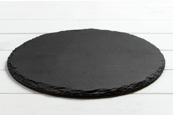 Zwarte leisteen ronde steen op houten achtergrond, bovenaanzicht, kopie ruimte — Stockfoto