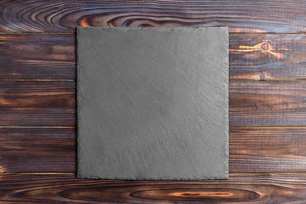 Slate blackboard on wooden table on wooden background — Stock Photo, Image