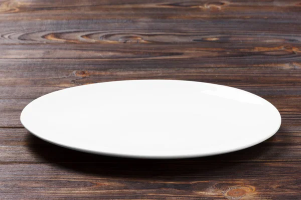 Assiette blanche sur la table brune en bois. Vue en perspective — Photo