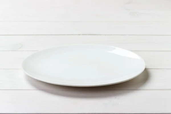 Λευκό στρογγυλό πιάτο σε φόντο λευκό ξύλινο τραπέζι. Προβολή προοπτικής — Φωτογραφία Αρχείου