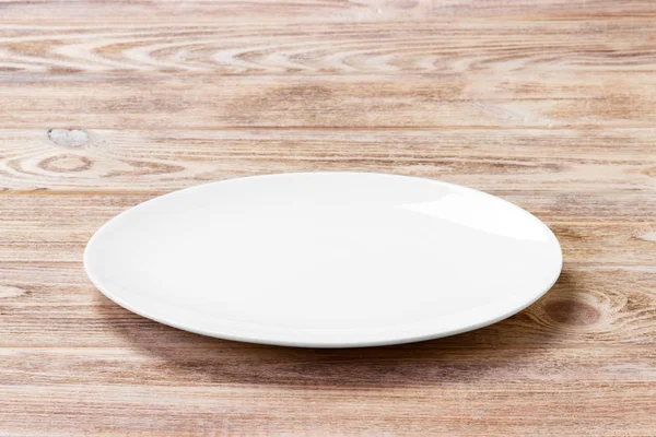 Assiette blanche sur la table brune en bois. Vue en perspective — Photo