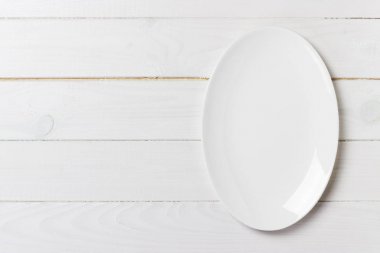 Tahta masada boş beyaz tabak. Üst görünüm