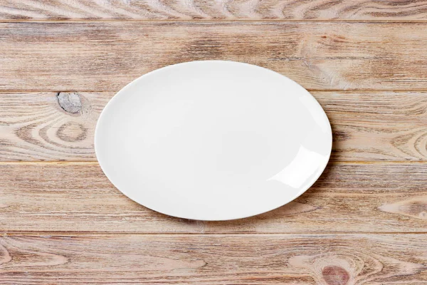 Empty white plate on wooden table. top view — Stock Photo, Image