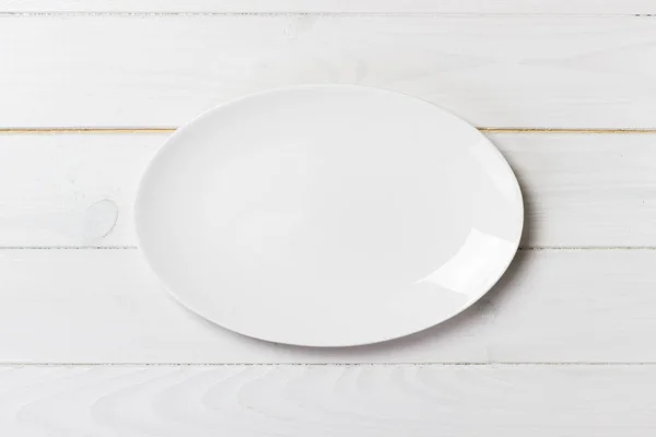 Вид сверху пустой белой тарелки на деревянном фоне — стоковое фото