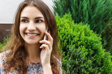 Güzel genç kadın Şehir Parkı içinde bir cep telefonu üzerinde söz