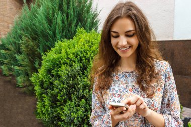 Bir akıllı telefon açık yeşil arka plana sahip tutan kız el