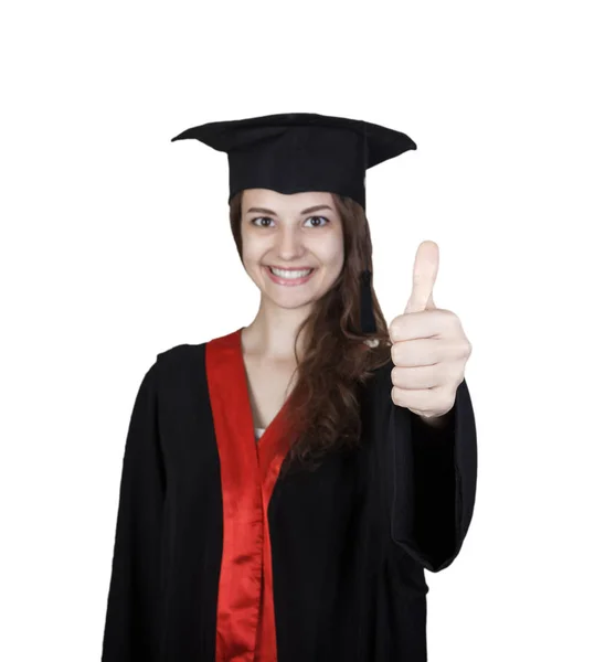 졸업 가운 엄지손가락을 보여주는 젊은 여자를 웃 고 — 스톡 사진