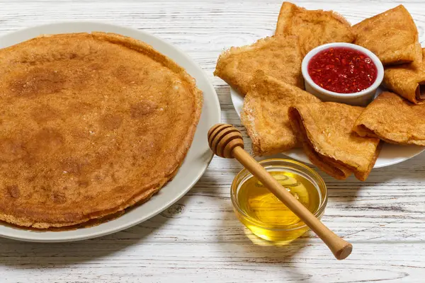 Pila de sabrosos panqueques con miel y mermelada de frambuesa en tarro en bachground de madera — Foto de Stock