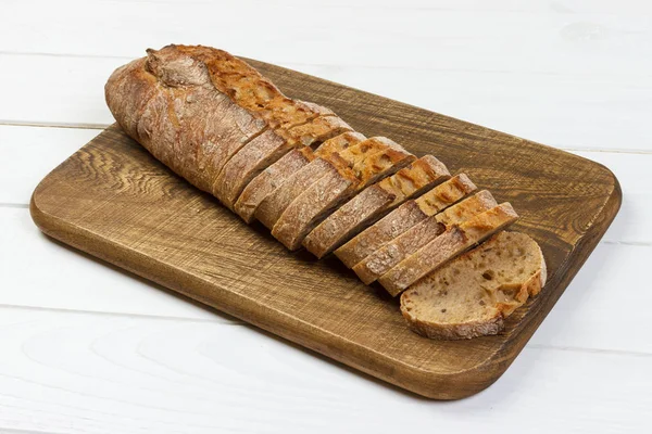 Französisches Baguette auf Schneidebrett auf weißem rustikalen Tisch — Stockfoto