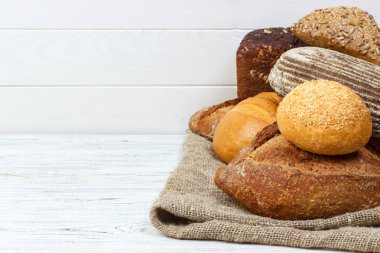 Çok arka plan ekmek. Ekmek pasta ve bakkal kavramı. Taze, sağlıklı çavdar ve beyaz somun, çul ve rustik ahşap masa, gıda closeup serpilir un