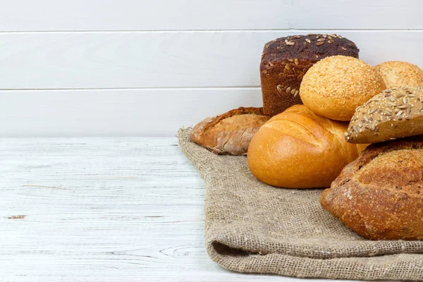 Surtido de pan recién horneado en mesa de madera — Foto de Stock